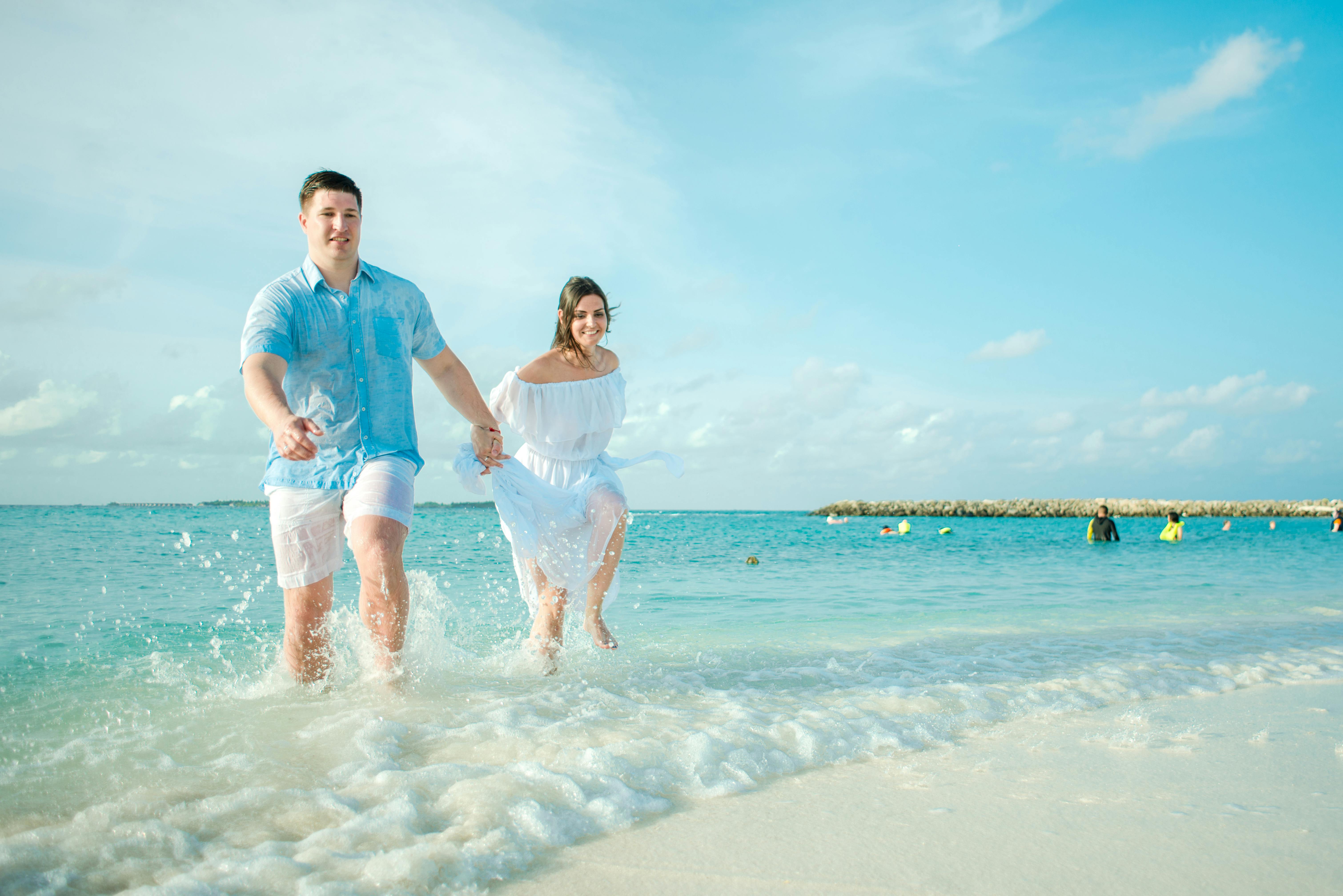 Koppel loopt hand in hand door zee op strand